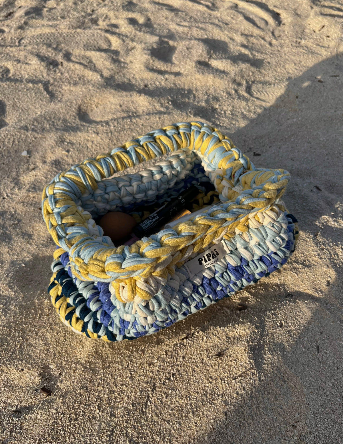 Clutch Capri jaune, bleu et blanc sur le sable