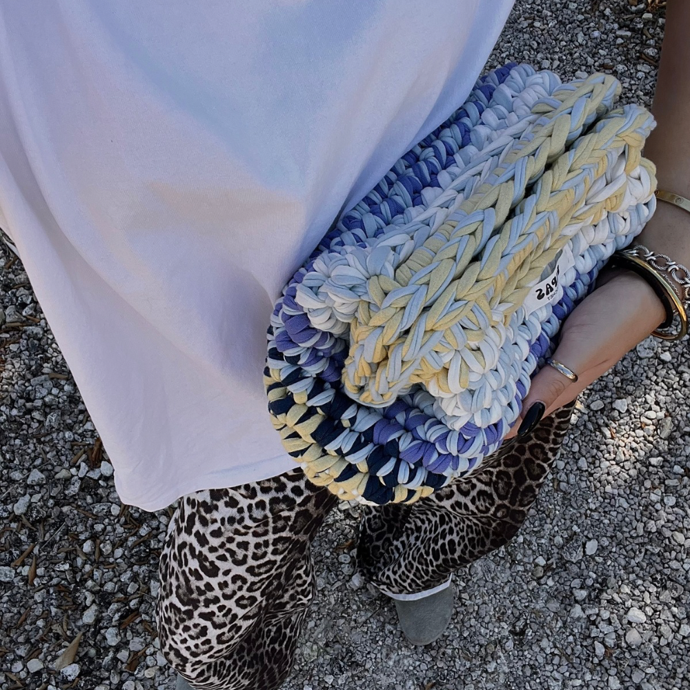 Clutch Capri porté à la main par une femme en t-shirt blanc et pantalon léopard