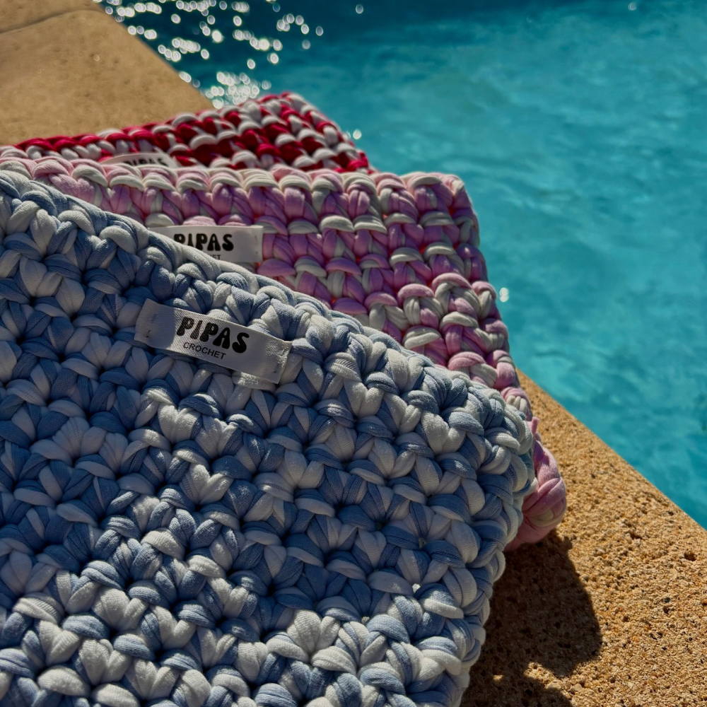 Pochettes Pipas bleues, blanches, et roses posées au bord de la piscine