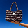Sac XXL Aspen marron et crème porté par une main avec le ciel bleu en arrière plan