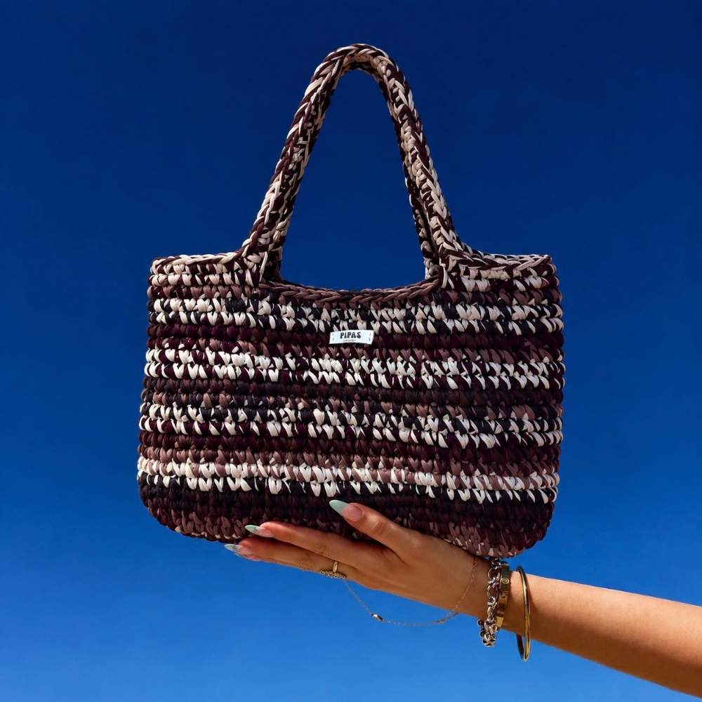 Sac XXL Aspen marron et crème porté par une main avec le ciel bleu en arrière plan